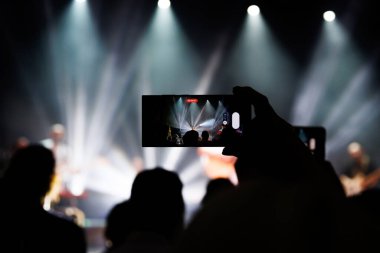 Canlı bir kalabalığın siluetleri popüler bir müzik konserinin keyfini çıkarıyor..