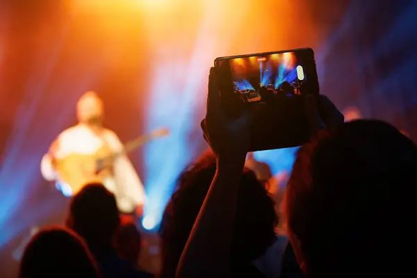 A crowded concert with a live performance, audience enjoying music and photographing the show with cellphones.