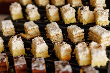 Siyah tepside beyaz kremalı, ısırık büyüklüğünde hindistan cevizli kekler..