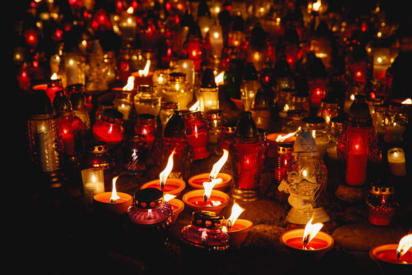 Many colorful lit memory candles in the dark. A beautiful display of colorful candles glowing in the night.