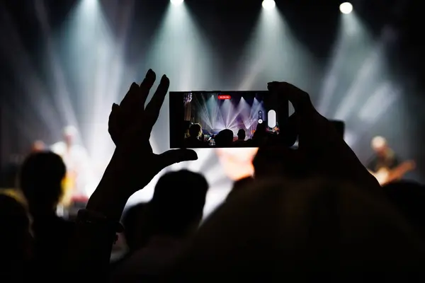 Silhouette of a crowd enjoying a live music performance with smartphone selfies