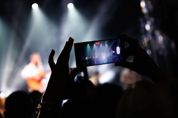 An audience enjoying a popular music concert with stage lights and smartphones