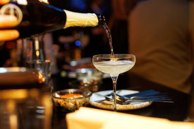Barmen bardağa köpüklü şampanya doldurur.