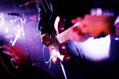Konser sırasında elektro gitar çalan bir müzisyenin yakın çekimi.