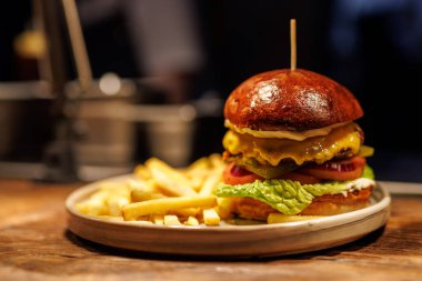 Erimiş peynir ve taze sebzelerle kaplanmış ve altın kızartma servisi yapan mükemmel pişirilmiş bir köfte içeren gurme burger başyapıtı..