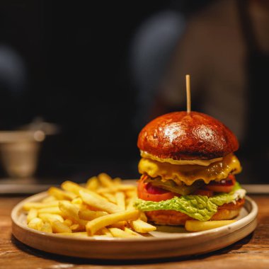 Erimiş peynir ve taze sebzelerle kaplanmış ve altın kızartma servisi yapan mükemmel pişirilmiş bir köfte içeren gurme burger başyapıtı..