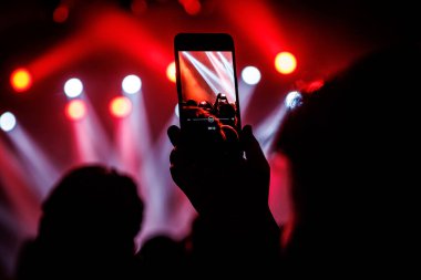 Anı sosyal ağlarda arkadaşlarla paylaşmak için konser sırasında akıllı telefonla fotoğraf çekmek