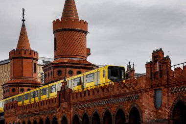 Yellow Berlin metro cars moving along the red brick historic bridge. clipart