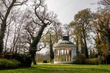 Büyüleyici bir çardak, yemyeşil bir yeşilliğin ortasında, yemyeşil bir bahçeye kurulmuş süslü beyaz bir çardak..