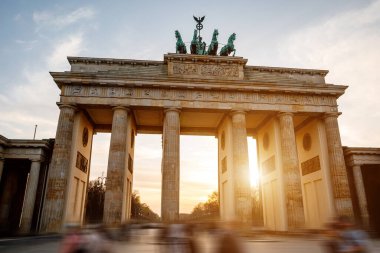 Berlin 'deki ikonik Brandenburg Kapısı yumuşak bir günbatımı gökyüzünün zeminine karşı.