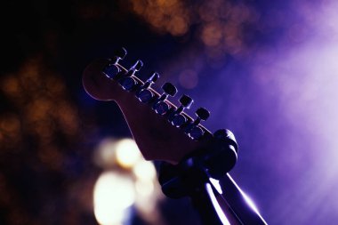 Gitar boyunluklarına yakın çekim. Sahnede konser ışıklarıyla aydınlatılmış gitar.