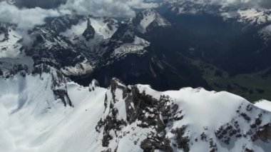 İnsansız hava aracı, karla kaplı zirveleriyle nefes kesici dağ manzarasının üzerinde uçuyor..