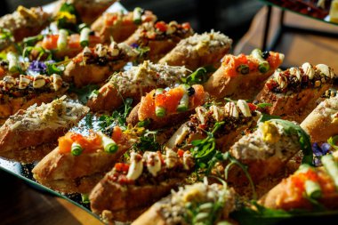 Zarif bir cam tabakta sunulan deniz ürünleri, yeşiller ve baharatlar içeren çeşitli malzemelerle nefis bir el yapımı bruschetta seçimi..