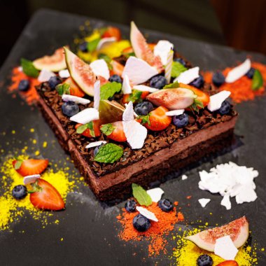 Tahta tabakta taze meyvelerle süslenmiş bozuk çikolatalı pasta.