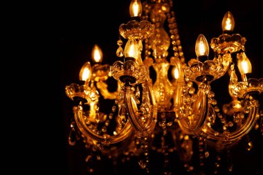 Koyu bir arkaplanı aydınlatan parlak ampullerle entrika ile tasarlanmış altın avize.