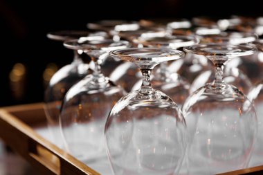 Ahşap tepside ters çevrilmiş boş kristal berraklığında şarap kadehleri.