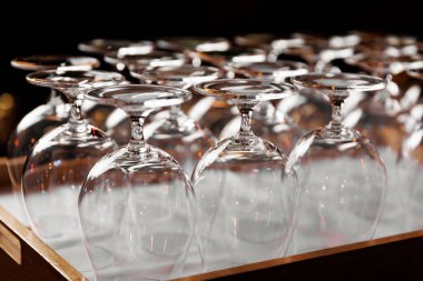 Ahşap tepside ters çevrilmiş boş kristal berraklığında şarap kadehleri.