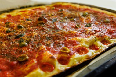 A freshly baked rectangular homemade Italian pizza with a golden crust clipart