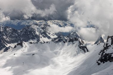 Majestic snow-capped mountain peaks under a dramatic cloudy sky clipart