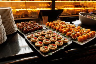 Bir gurme aperatifleri dizisi, tepsilerde zarif bir şekilde sunuluyor. Turtalar ve şiş domatesli mozzarella ısırıkları lüks toplantılarda damak zevkini tatmaya hazır..