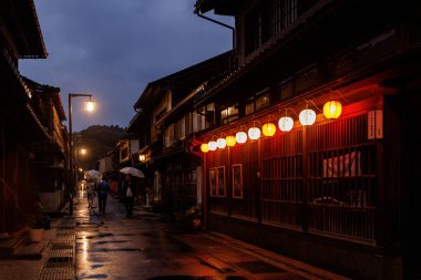 Kanazawa, Japonya - 23 Ekim 2024: Yağmurlu, sakin bir akşamda hafifçe parlayan fenerlerin yer aldığı loş ışıklı bir caddeyi tasvir eden sakin bir sahne