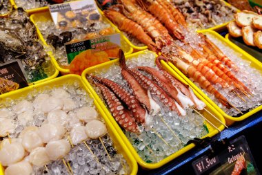 Karides, ahtapot ve deniz tarakları da dahil olmak üzere renkli taze deniz ürünleri dizisi buzda güzelce sunuluyor.