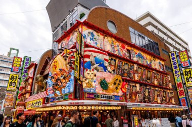 OSAKA, Japonya - 26 Ekim 2024 Japonya 'da renkli bir bina, karmaşık tasarımlar ve hareketli bir sokak hayatı
