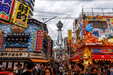 OSAKA, Japan - October, 26, 2024: A bustling street scene in Osaka, Japan, filled with neon lights, lively crowds, and colorful storefronts clipart