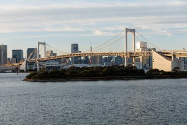 Tokyolar gün batımında Gökkuşağı Köprüsü 'nü etkileyici bir şehir arkaplanıyla aydınlattı.