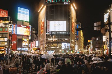 Tokyo, Japonya - 3 Kasım 2024: Shinjuku şehir merkezi geceleri ışıklı neon ışıkları ile. Shibuya 'daki insanlar geçitten geçiyorlar.