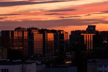 Canlı bir günbatımı genişleyen şehir manzarasına parlak renkler yansıtıyor. Gün batımında evin parlaklığı
