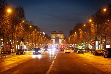 PARIS, FRANCE - 02 / 17 / 2025: Arabalar ve otobüslerle dolu yoğun bir cadde. Champs Elysees 'de Zafer Takı ufukta görünüyor.