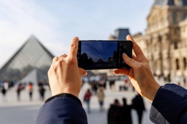 Bir kişi Eyfel Kulesi 'nin cep telefonuyla fotoğrafını çekiyor.