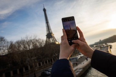 Birisi Eyfel Kulesi 'nin cep telefonuyla fotoğrafını çekiyor.