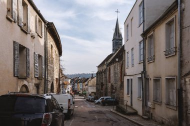 Arka planda kilise olan dar bir cadde. Cadde binalarla ve park edilmiş arabalarla dolu.