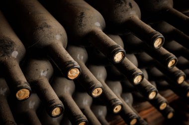 Mantar tıpalı bir sıra şarap şişesi. Şişeler üst üste istiflenmiş.