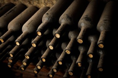 Mantarlı bir sıra şarap şişesi. Şişeler üst üste istiflenmiş.