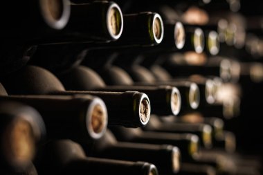 Mahzendeki Şarap Şişeleri Koleksiyonu. Şarap mahzeninde depolanmış tozlu şarap şişelerinin yakın çekim görüntüsü..