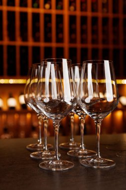 Bir sıra şarap kadehi tezgahın üzerine dizilmiştir. Bardaklar temiz ve boş görünüyor.