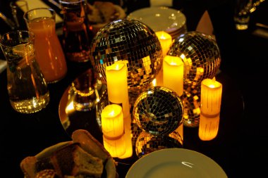 Yansıtıcı disko topları ve titreyen mumların yer aldığı mum ışığında yemek ve kutlama için sıcak ve davetkar bir ortam oluşur..