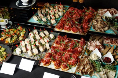 Cazibeli büfe ziyafetinde çeşitli şarküteri, peynir ve aperatifler yaratıcı bir şekilde tabakta sunuluyor..