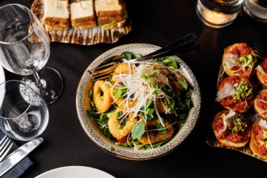 Bir tabak salatalı yemek ve bir kase kızarmış yiyecek. Masa bir şarap kadehi ve çatalla hazırlandı.