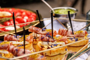 Close-up of cheese and salami skewers served on toasted bread. Elegant table setting with catering dishware.