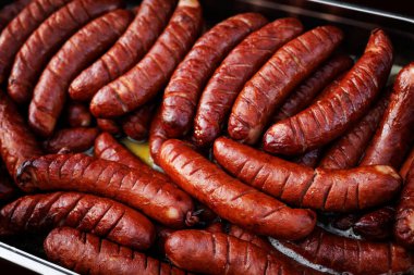 Close-up of grilled sausages served in a tray with oil. Cooked and ready to serve.