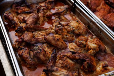 Salamurada kızarmış tavuk kanatlarıyla dolu metal tepsi. Kahverengi kıtır kıtır doku ve yağlı yüzey.