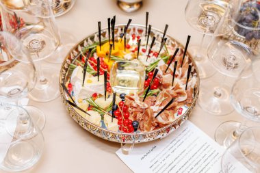 Decorative appetizer platter with cheese, cold cuts, herbs and berries. Presented on elegant tray with sticks.