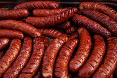A tray full of grilled sausages ready to serve at a cookout. High detail of texture and color.