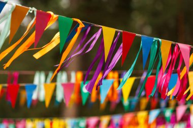 Brightly colored pennant banners and ribbons fluttering in the wind. Festive decoration in outdoor setting.