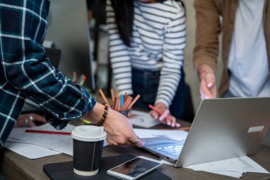group of young people working on a project.Colleagues standing together brainstorming working ideas All hands colleague join hands presenting ideas to laptop in conference room
