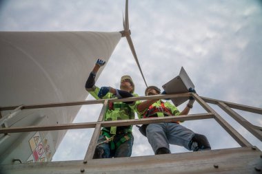 group of workers repairing wind turbines using forceRenewable wind power generation workers are marching with the team together into a field of turbines.